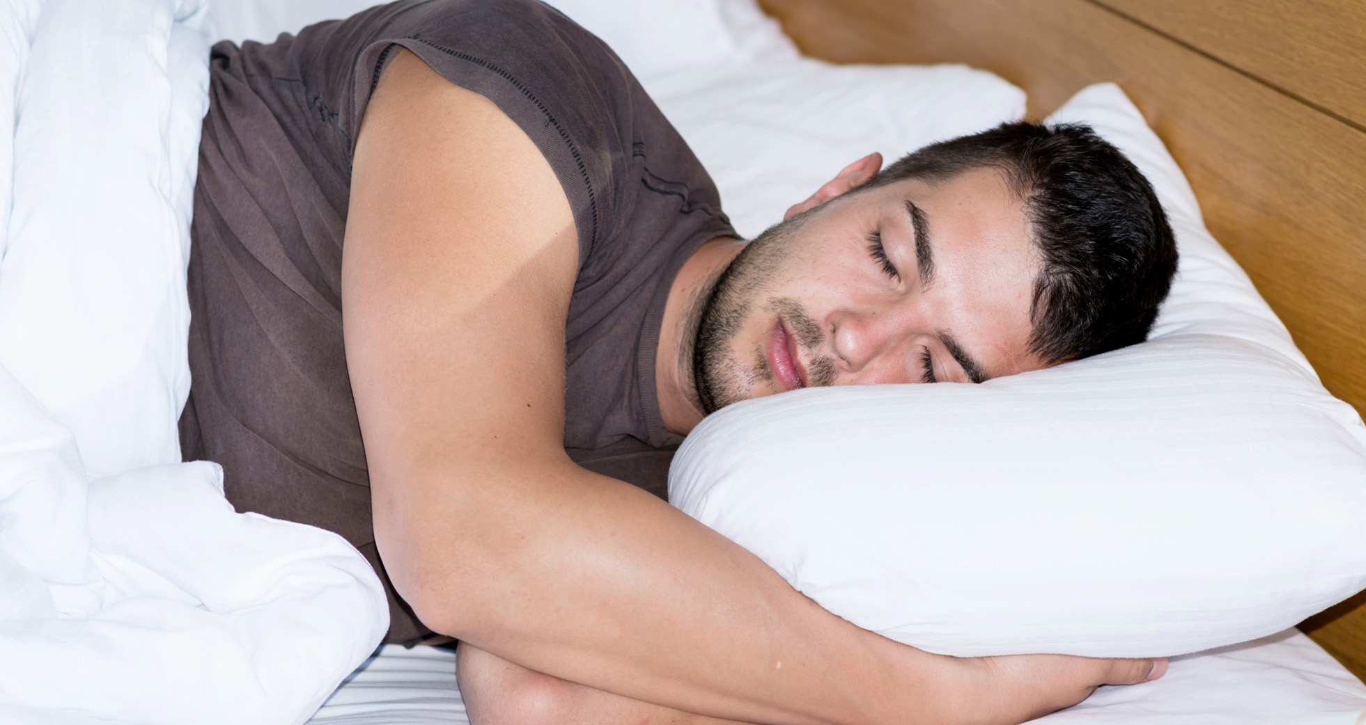 A man sleeping on his side with his hands folded underneath his head