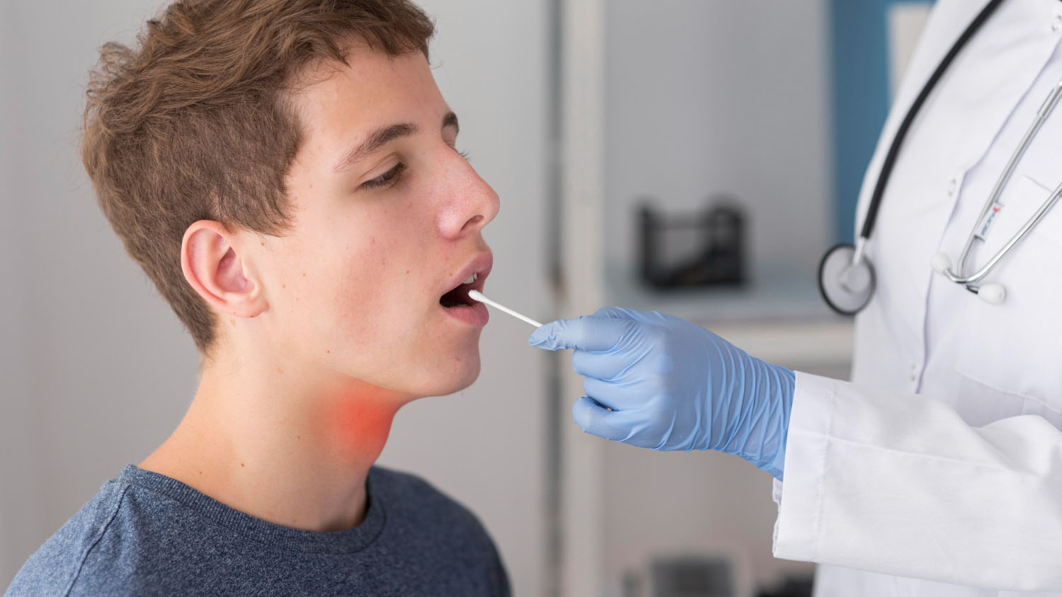 A medical professional swabbing a young man mouth for testing