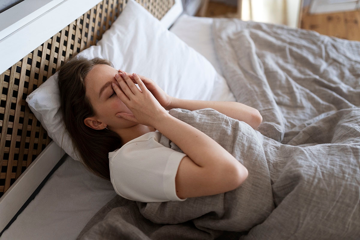 A woman in bed, unable to sleep, experiencing sleep deprivation
