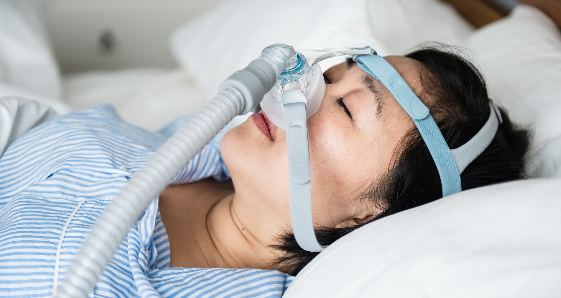 A woman using a CPAP device sleeping on a CPAP pillow.