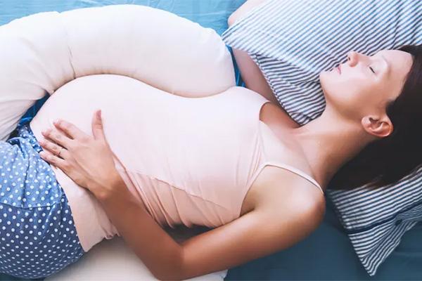 A pregnant person sleeping with a pillow between their legs.