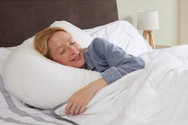 Someone sleeping under a comforter on a bed.