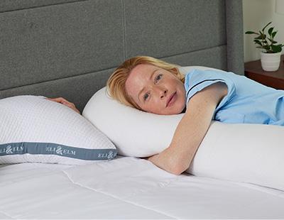 Woman Lying on Bed Hugging a Pregnancy Pillow