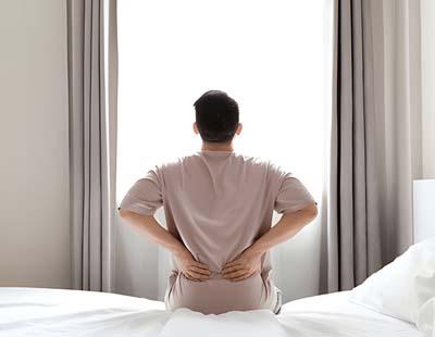 Tired man suffering from back pain after sleeping