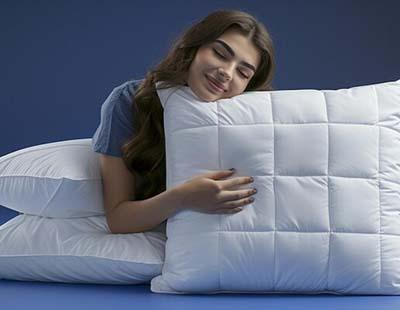 A woman reclines on a pillow, surrounded by three additional pillows, creating a cozy and relaxed atmosphere