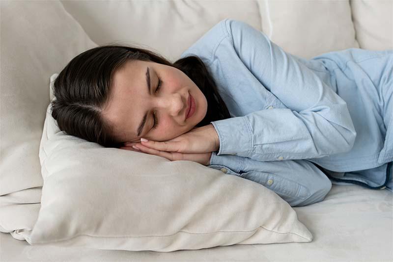 A woman sleeping with her hands folded in prayer position and tucked under her head