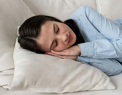 A woman sleeping with her hands folded in prayer position and tucked under her head