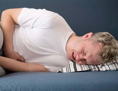 A man agonizing in pain while sleeping due to a urinary tract infection