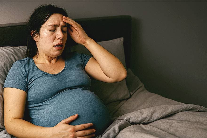 A pregnant woman seemingly sweating while sleeping.