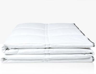 A white weighted comforter by Eli & Elm kept folded