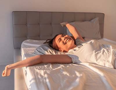 A woman waking up after a comfortable and good night’s sleep