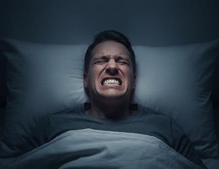 A man clenching his teeth while sleeping.