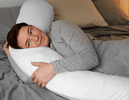 A woman using a body pillow.