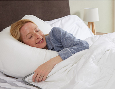 Someone sleeping under a comforter on a bed.