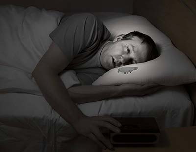 A man unable to sleep due to high humidity in the bedroom