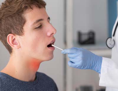 A medical professional swabbing a young man mouth for testing