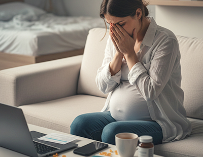 A pregnant woman sitting, visibly stressed
