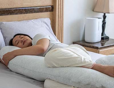 A pregnant woman sleeping on her side with a full-body pregnancy pillow