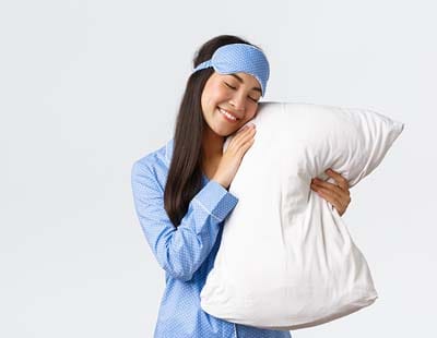 A woman holding a white pillow, caressing it