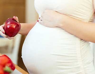A pregnant woman holding an apple