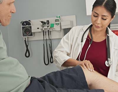 A female doctor checking a patient’s knee movement after knee replacement surgery