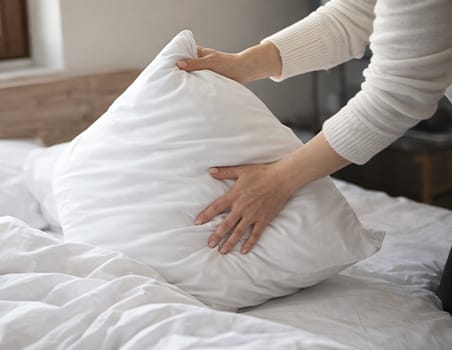 A hand fluffing a pillow