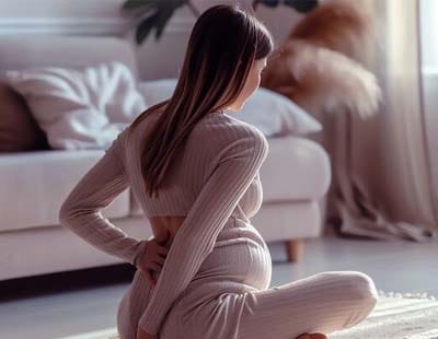 A pregnant woman sitting on a mat suffering from hip pain