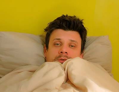 A man waking up in the morning tired and shaking