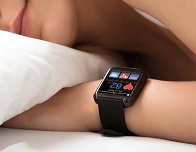 A girl is peacefully sleeping, her wrist adorned with a watch displaying her heartbeat on the screen