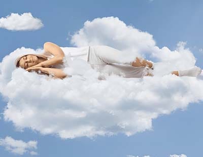 A woman in a deep sleep rests on a soft cloud, surrounded by a calm, dreamy sky, symbolizing serenity and comfort