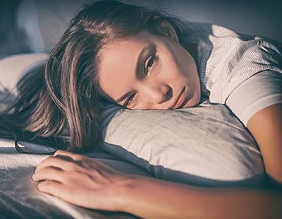 Tired woman lying in bed can’t sleep