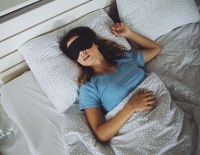 A woman sound asleep wearing a black sleep mask