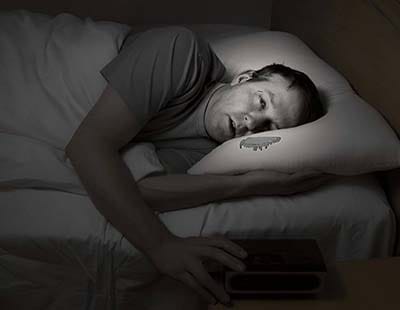 A man unable to sleep due to high humidity in the bedroom