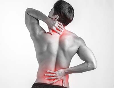 A man wrapping his hands at the back of his neck and his lower back due to pain