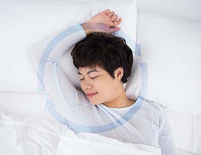 A woman smiling in her sleep, emphasizing on a peaceful sleeping experience