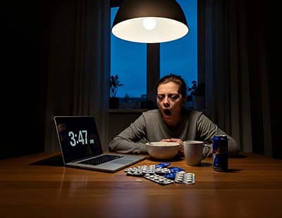 A woman with a disturbed sleep cycle, with medicines and a laptop showing late timing, on the table