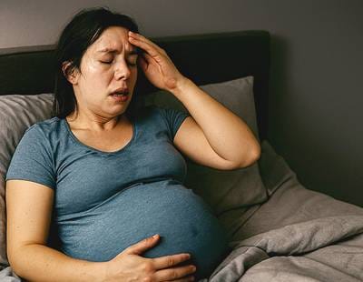 A pregnant woman seemingly sweating while sleeping.