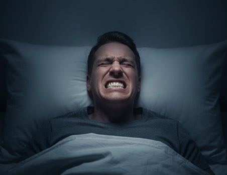 A man clenching his teeth while sleeping.