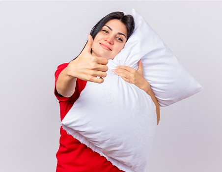 A woman posing with a white pillow.