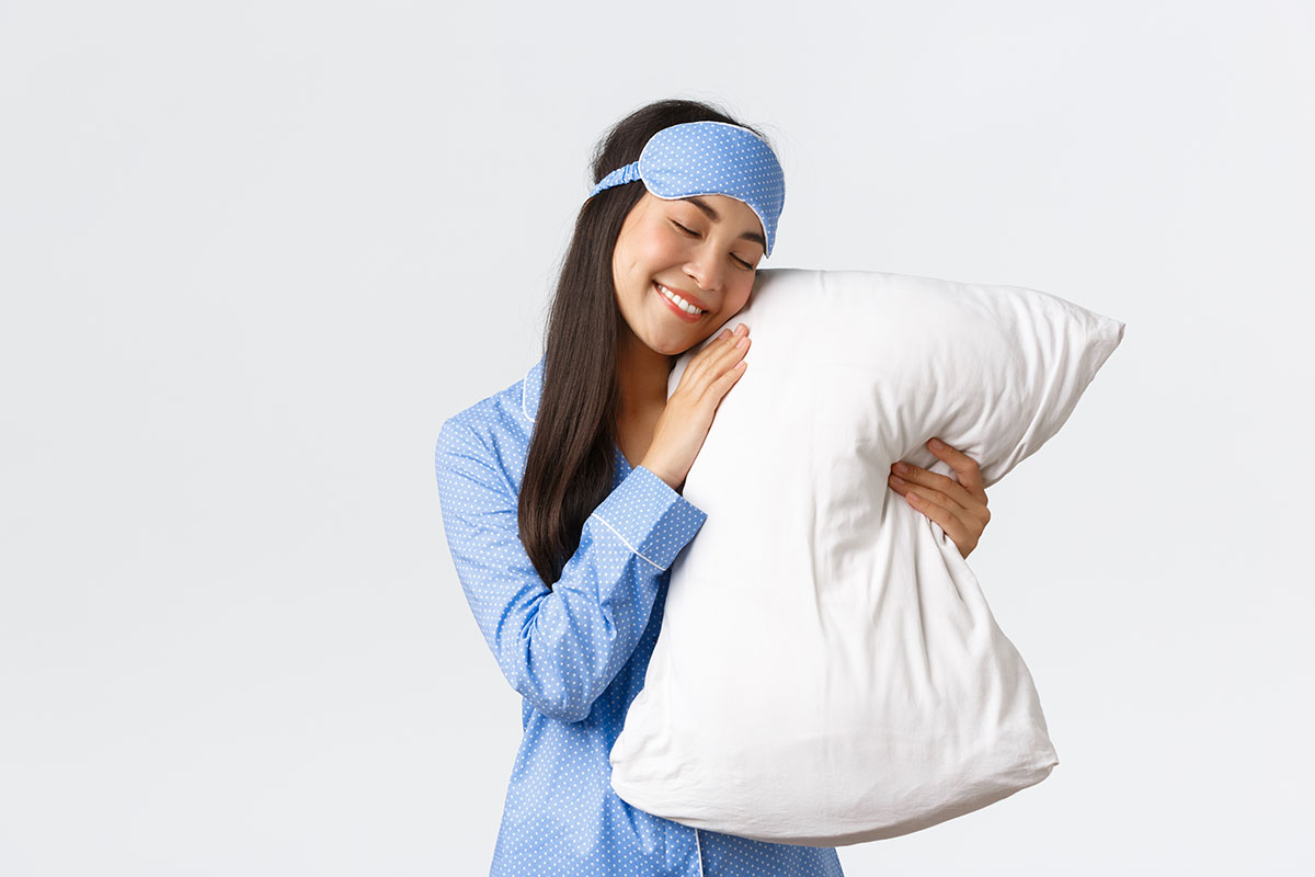 A woman holding a white pillow, caressing it