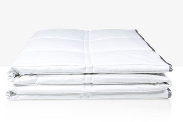 A white weighted comforter by Eli & Elm kept folded