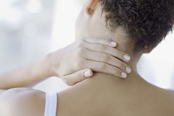 A woman keeping a plan on the back of her neck in pain