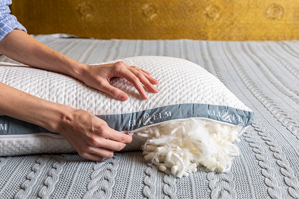 A person’s hand unzipping the adjustable latex pillow by Eli & Elm
