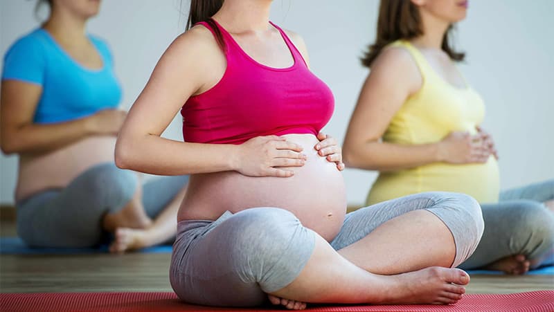 Pregnant women sitting with crossed legs and exercising