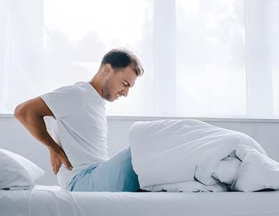 A man agonizing in his lower pain after waking up