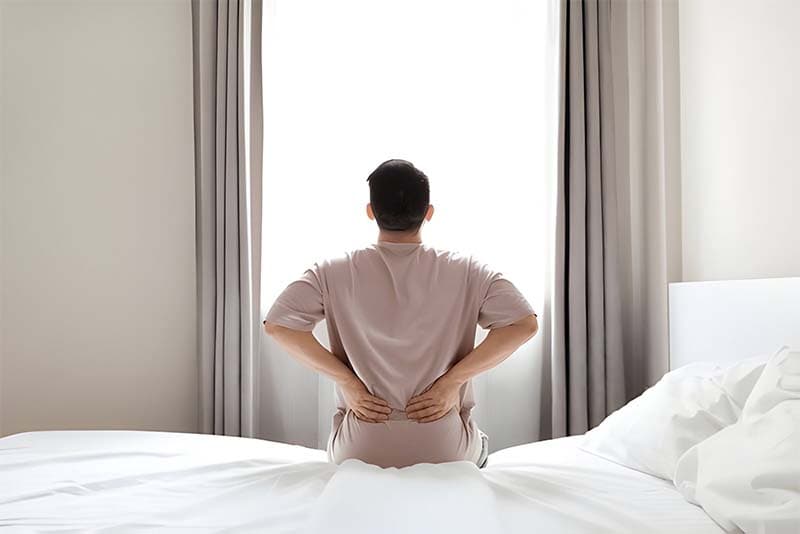 Tired man suffering from back pain after sleeping