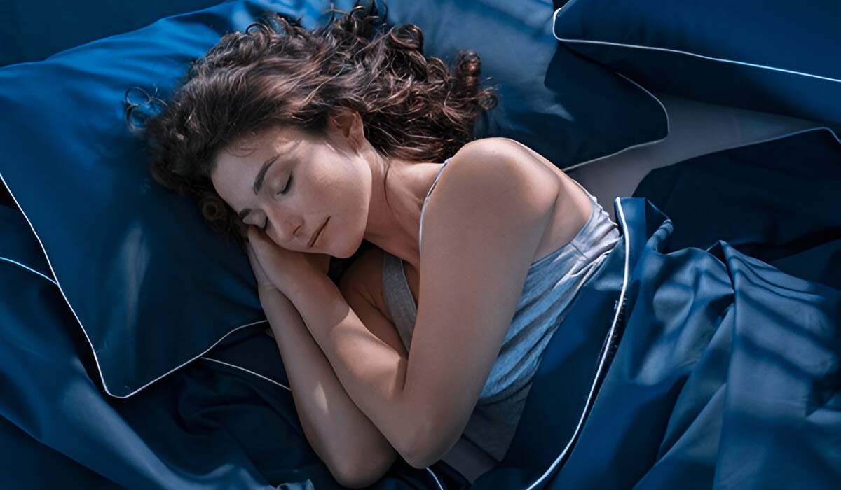 A Woman in a deep sleep on a blue bed setting