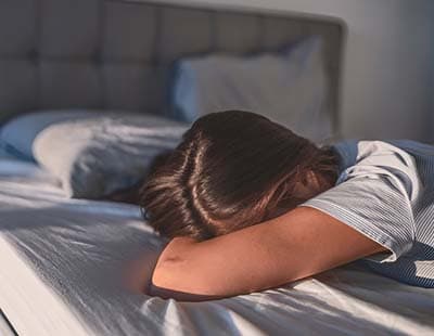 A woman lying on her stomach on a bed, unable to wake
