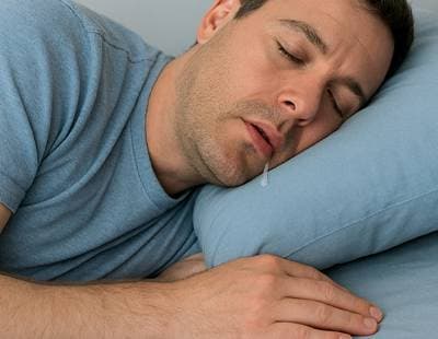 A man sleeping with his mouth slightly open simultaneously drooling.