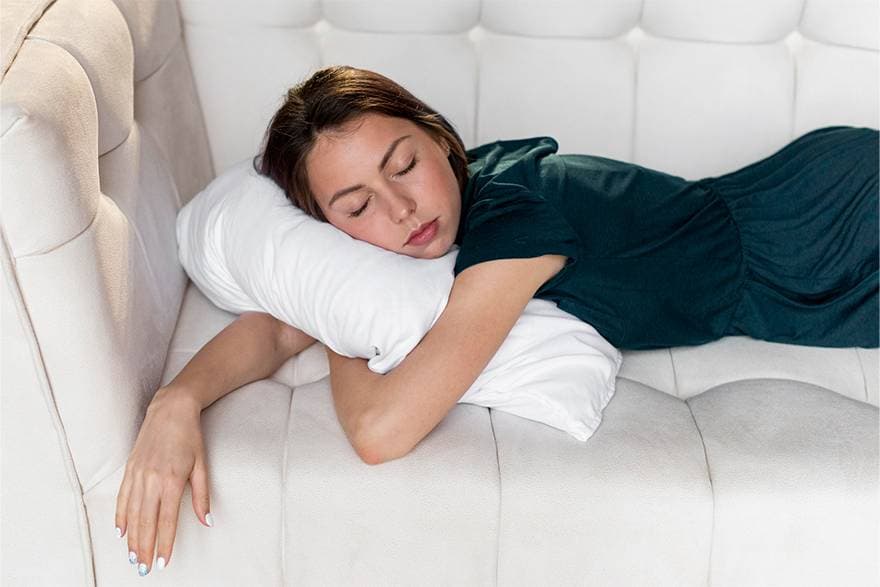 A woman sleeping on her side with her arms wrapped around a pillow.